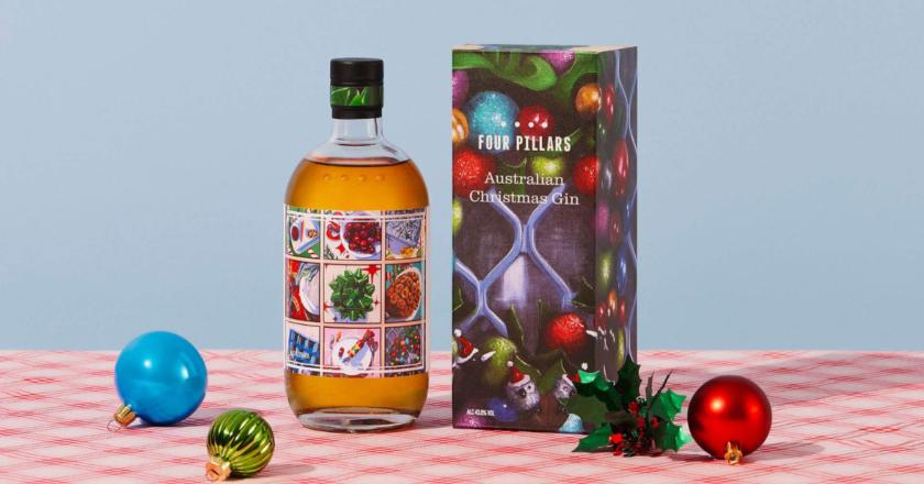 Four Pillars Christmas Gin 2023 bottle featuring boxed packaging and round bauble Christmas ornaments on table.