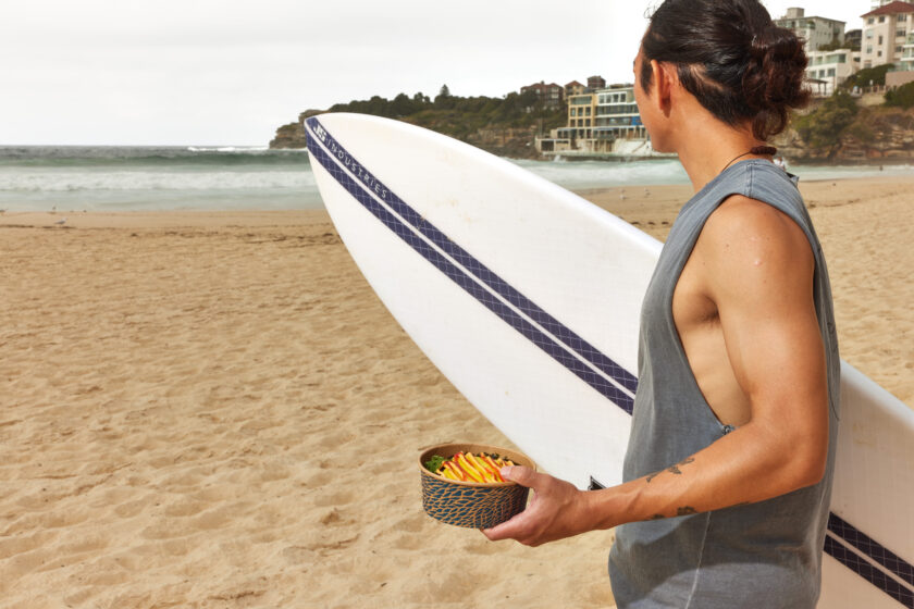 Man with DOPA and surfboard on Bondi Beach.