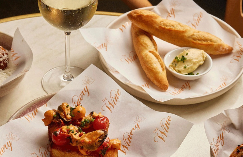 The Winery food on plates including a baguette with butter and a glass of white wine