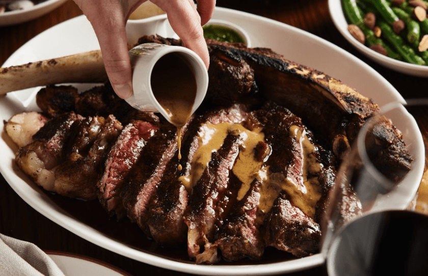 Drool-worthy steak with sauce being pored on top