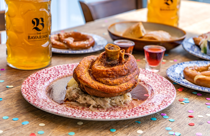 Image of food on red and white plate with German snacks and beers in the background