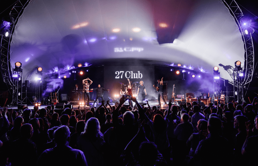 27 club playing a gig to a large crowd of people at an outdoor stage 