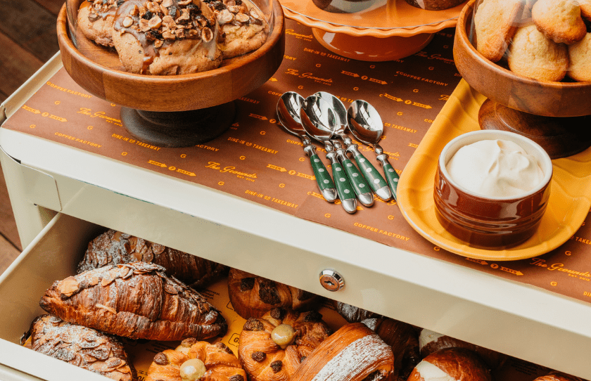 Pastries in a cupbord with whipped cream, croissants and cookies