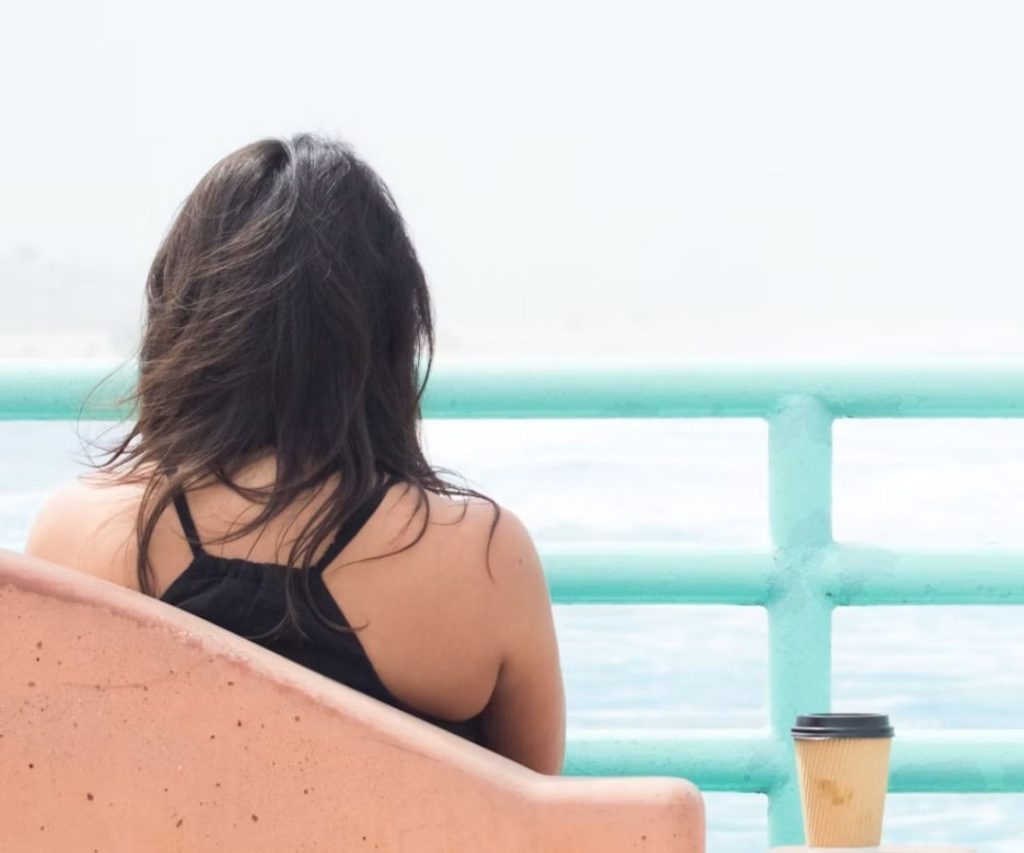 A woman drinking coffee by the beach